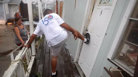 Getty Images A man tries to kick open a door of an apartment to find his friends