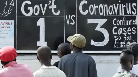 People reading a blackboard news board in Monrovia, Liberia - Monday 30 March 2020
