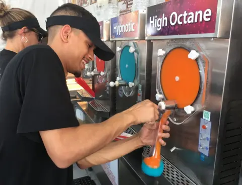 BBC A man pours colourful frozen alcohol