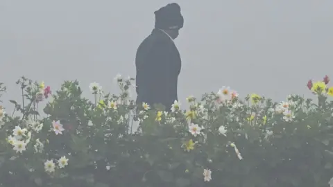 Getty Images A security person walks through thick fog at Mahatma Gandhi memorial in Delhi on 30 January