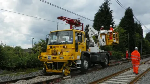 Truck on rails with workers repairing wires