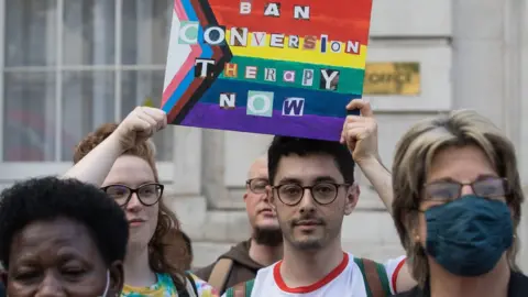 Mark Kerrison Protestors with sign saying ban conversion therapy now