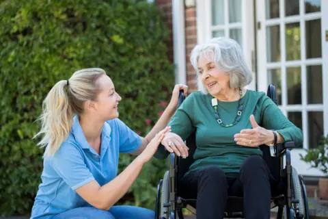 Getty Images Healthcare assistant with elderly care home resident