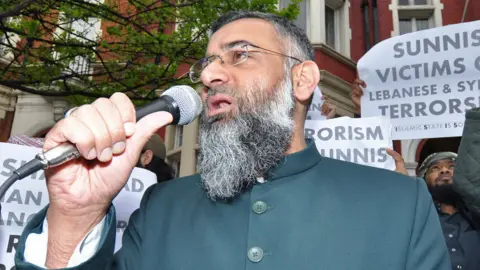 Demotix Poster behind Choudary includes small print words "Islamic State Is Solution", spelling ISIS