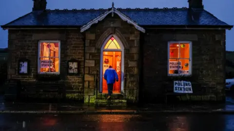 Getty Images A man enters a polling station as snow falls in the North Pennines