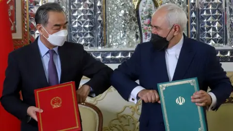 Reuters Chinese Foreign Minister Wang Yi and Iranian Foreign Minister Mohammad Javad Zarif bump elbows during the signing ceremony of a 25-year co-operation agreement in Tehran, Iran (27 March 2021)