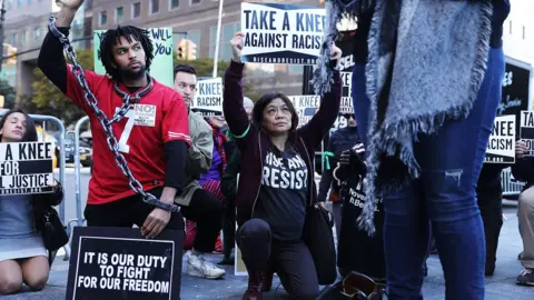 Getty Images Protestors hold a demo outside an NFL meeting in New York, 2017