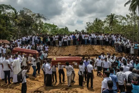 Carl Court / Getty Images Coffins are carried to a grave during a mass funeral at St Sebastian's Church on 23 April in Negombo, Sri Lanka.