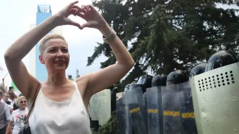 Getty Images Maria Kolesnikova making a heart sign with her hands in front of a group of riot police in Minsk