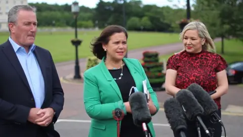 PA Media Sinn Fein President Mary Lou McDonald (centre) accompanied by Michelle O'Neill and Conor Murphy, talking to media ahead of a meeting with NI Secretary Brandon Lewis.