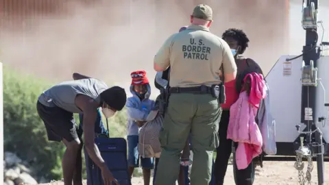 Getty Images A family from Honduras turns themselves into the Border Patrol after crossing the United States border from Mexico on April 29, 2021 near Yuma, Arizona