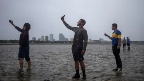 Reuters People in Tampa take photographs in drained bay with skyline in background