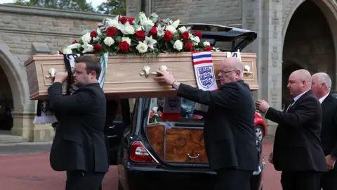 PA Media The coffin is carried into the service at West Road Crematorium