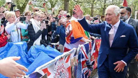Reuters King Charles waving to a gathered crowd at The Mall