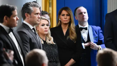Bloomberg via Getty Images Melania Trump stands next to Karoline Leavitt, Pete Hegseth and Marco Rubio and other officials as Trump responds to reporters questions in the White House.