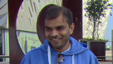 Vishnu smiling, wearing a blue hoodie. The Titanic museum is in the background.