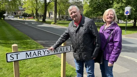 BBC / Naj Modak Couple pointing at street sign