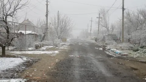 Goktay Koraltan/ BBC Empty residential street with snow on the ground in the city of Pokrovsk 