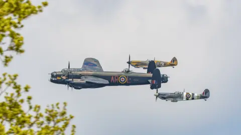 Claire Hartley A Lancaster Bomber flies through the sky flanked by two Spitfires