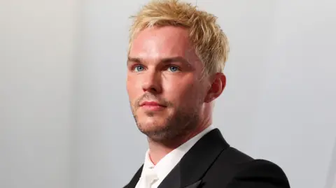 Nicholas Hoult looking slightly off camera with dyed blond hair, white shirt and tie and black dinner jacket at the 2026 Vanity Fair Oscar Party held at the Los Angeles County Museum of Art