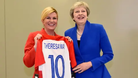 AFP/Getty Images Croatia President Kolinda Grabar-Kitarovic (L) offering a Croatia national football team jersey to British Prime minister Theresa May (R) at the NATO headquarters in Brussels