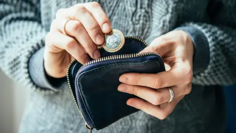 Getty Images Woman holding money and purse