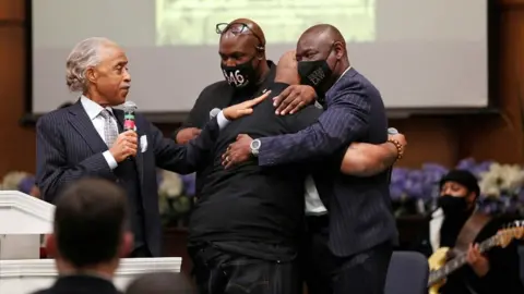 Reuters Terrence Floyd, brother of George Floyd, is comforted by Rev Al Sharpton (L), his brother Philonise Floyd, and attorney Ben Crump (R), during a prayer vigil the day before opening statements in the trial of former police officer Derek Chauvin, who is facing murder charges in the death of George Floyd, in Minneapolis, Minnesota, on 28 March 2021