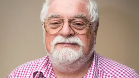 North Petherton Town Council a white man with grey hair and beard and glasses and a pink checked shirt