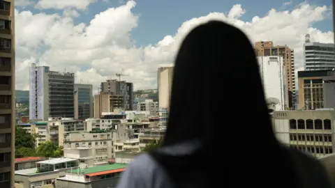 Paulo Koba / BBC An unidentified woman stands in front of the Caracas skyline