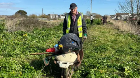  Bradley Thompson A man pushing a wheel barrow full off rubbish