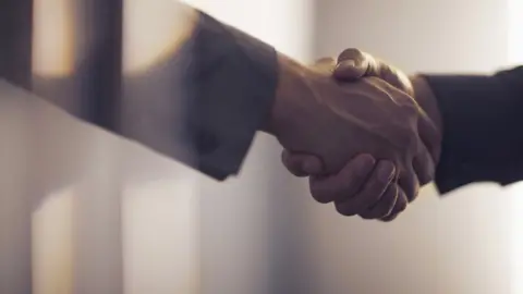 Shannon Fagan/Getty Hand shaking