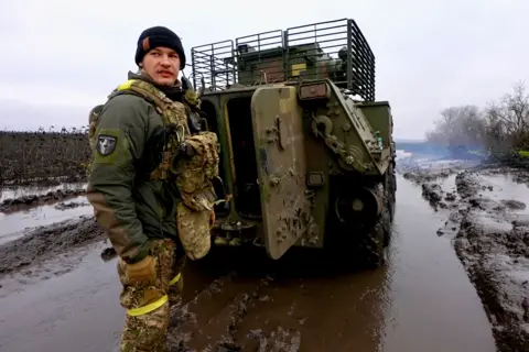 BBC/ QUENTIN SOMMERVILLE Eugene stands in front of the APC