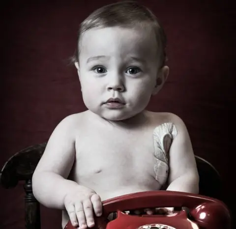 Debbie Todd A very young boy holds a phone