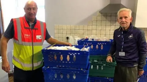 Mydrim Davies Foodbank manager Mydrim Davies (right) with the Tesco delivery driver and the donated food