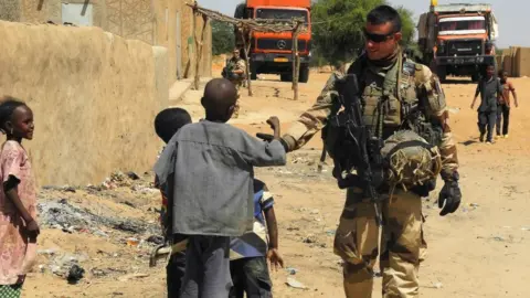 Getty Images A soldier of France's Barkhane mission stands next to children as he patrols in In-Tillit on November 1, 2017 in Mali