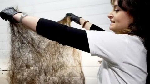 Adele holding up a mat made of human hair.