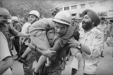 Getty Images Firemen rescue people during the fire at Uphaar Cinema in 1997