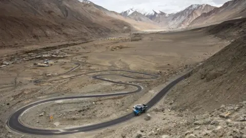 Getty Images Workers ride on the back of a truck along Pangong Lake road in northern India's Ladakh region