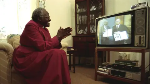 Getty Images Archbishop Desmond Tutu applauds as he watches Nelson Mandela and South African President FW de Klerk receive their Nobel Peace Prize for ending Apartheid in South Africa