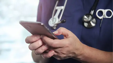 Getty Images Doctor holding a mobile phone