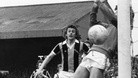 Mirrorpix via Getty Images Black and white match picture of Hull City playing Sunderland in April 1976 the Hull players are defending their goal and wearing the striped shirts similar to the new design