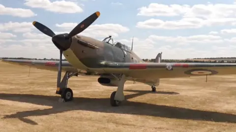 A Hurricane plane standing on dried yellow grass.