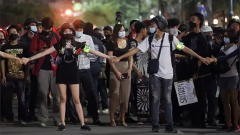 Reuters A group of protesters hold hands as they march through Bangkok