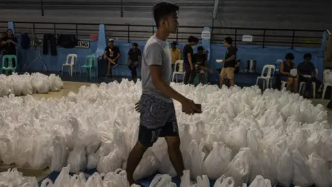Getty Images Volunteers prepare packed rice as aid to affected residents as Typhoon Mangkhut approaches on September 14, 2018 in Tuguegarao city, northern Philippines