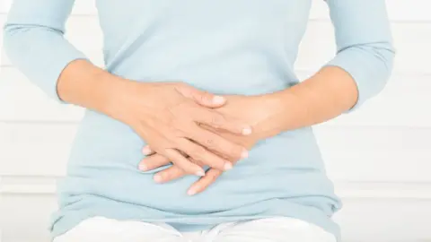 Getty Images Woman holding her hands on her tummy