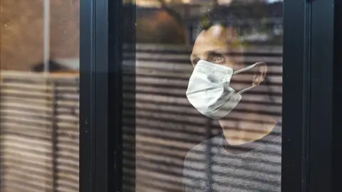 Getty Images man in mask looking through window