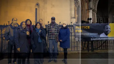 Justice for Christopher Kapessa A group of campaigners gather outside a court building next to a banner reading 'Justice for Christopher Kapessa'.