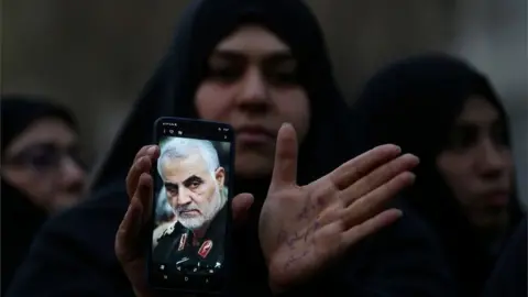 Reuters A woman demonstrates over the killing of top Iranian military commander, General Qasem Soleimani, 3 January 2020