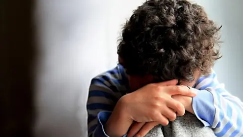 Getty Images A sad child with head in hands