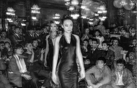 ADRIAN BRADSHAW Models walk along a catwalk